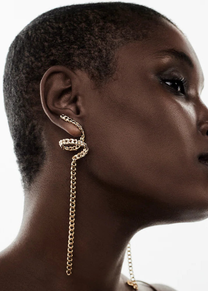 Woman wearing a gold chain earring with a white background