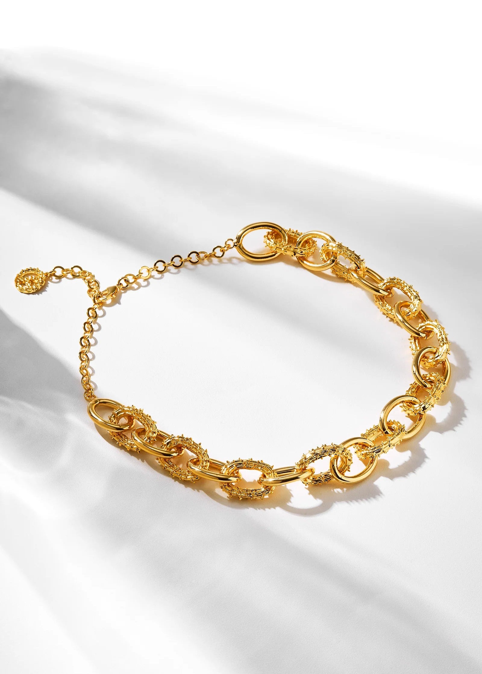 Gold chain bracelet on a white fabric background