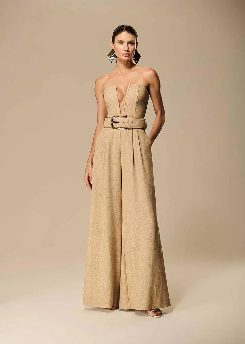 Woman wearing a beige strapless jumpsuit with a belt on a beige background