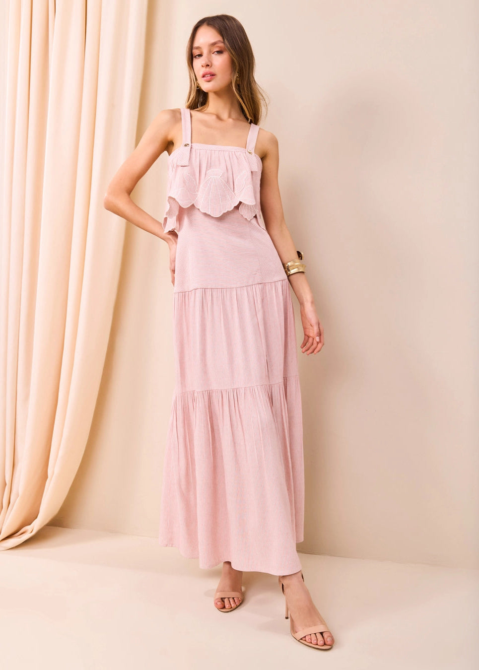 Woman wearing a pink dress against a beige curtain background