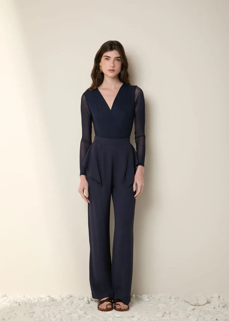 Woman wearing a navy blue jumpsuit against a plain background