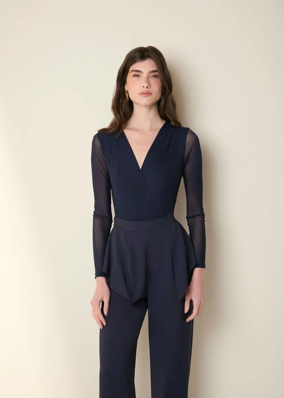 Woman wearing a navy blue jumpsuit against a plain background