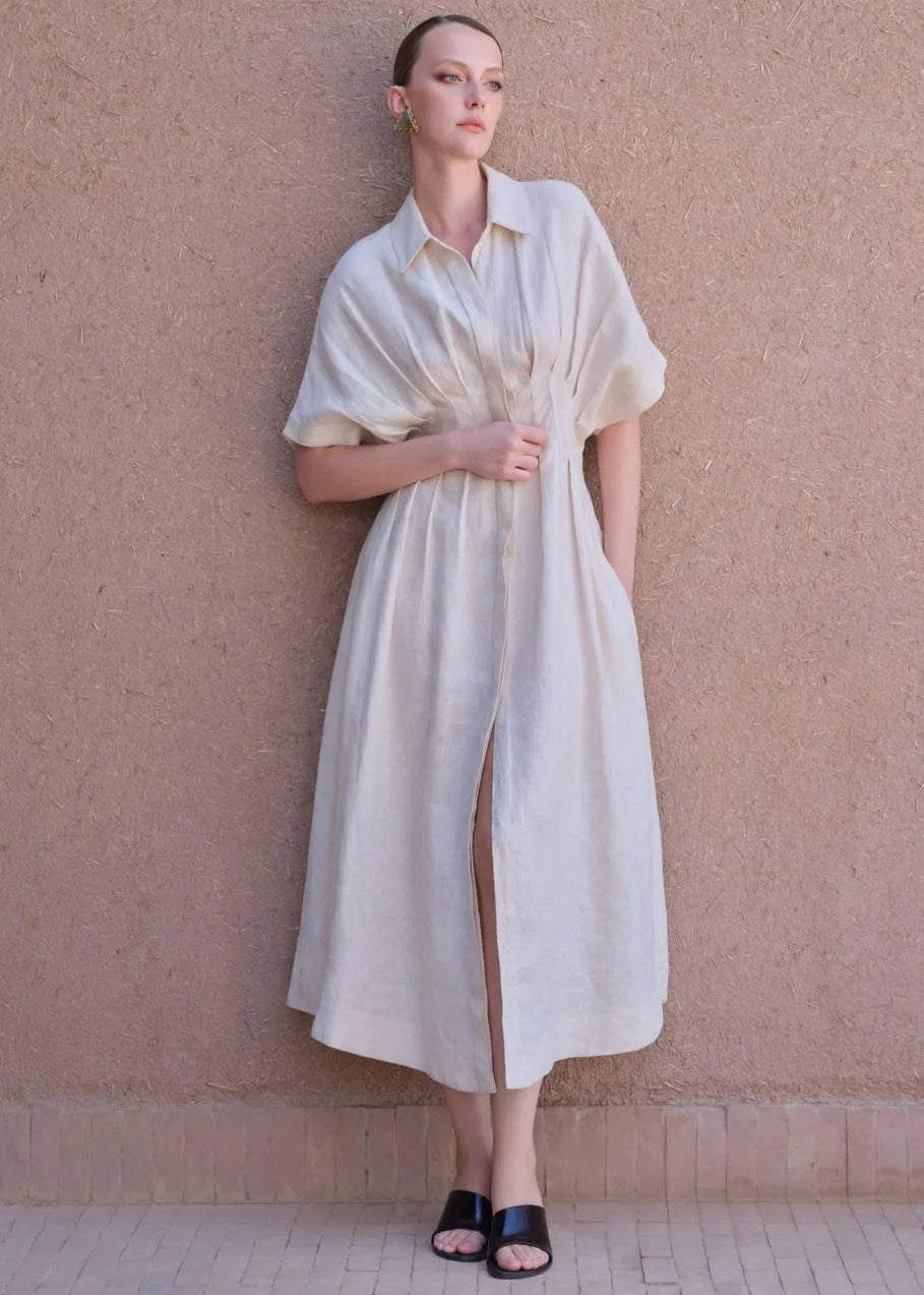 Woman wearing a white dress against a beige wall