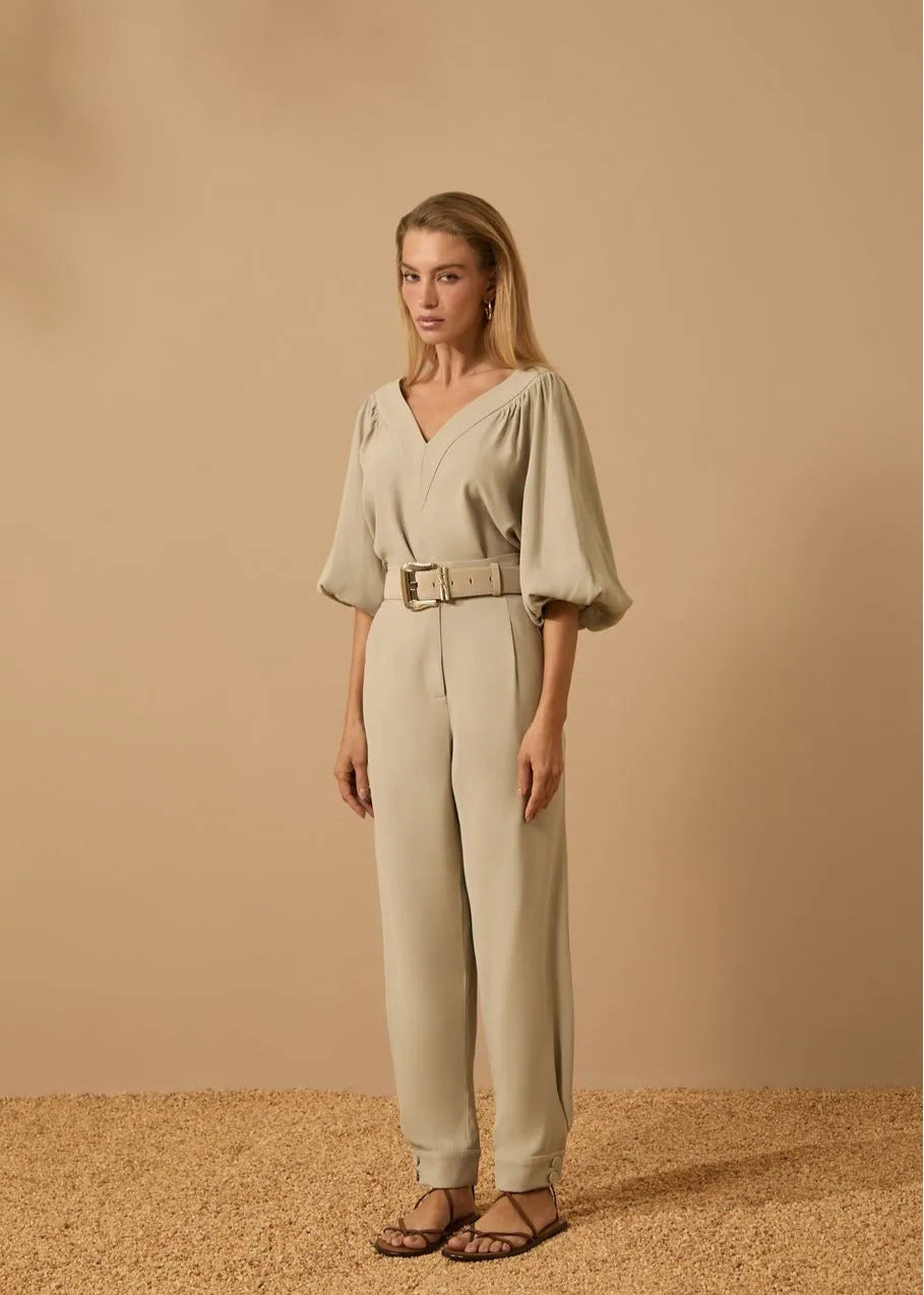 Woman wearing a beige outfit with a belt against a beige background