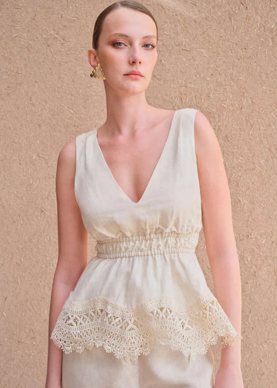 Woman wearing a white dress with lace details against a beige background