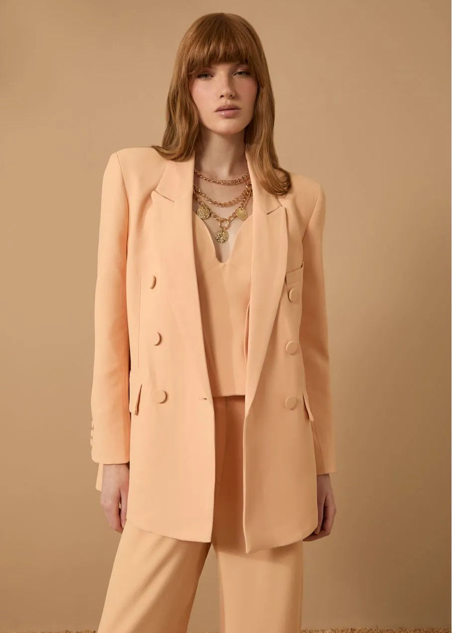 Woman wearing a peach suit against a beige background