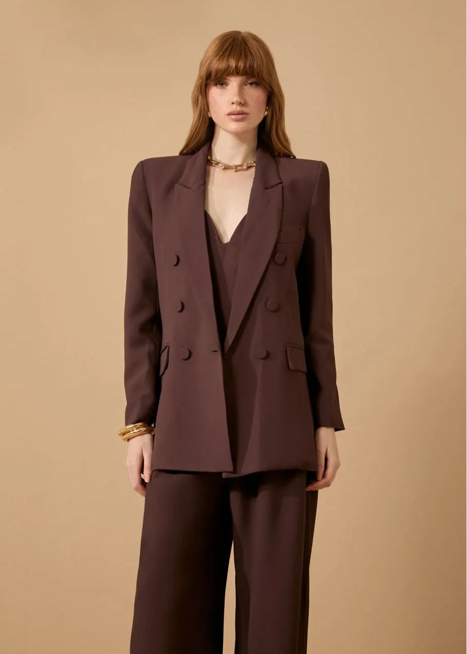 Woman wearing a brown suit against a beige background