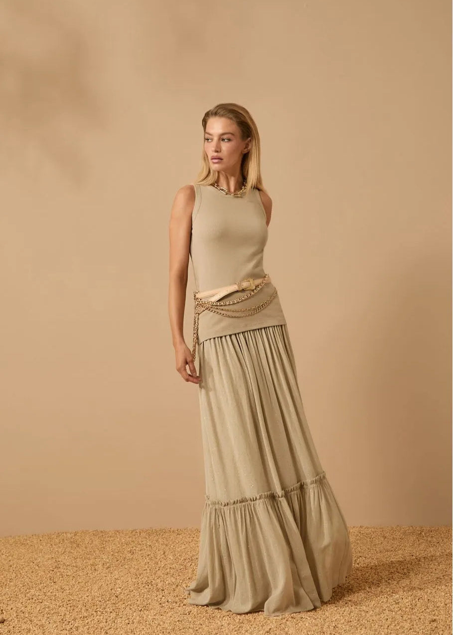 Woman wearing a long, light brown dress against a beige background