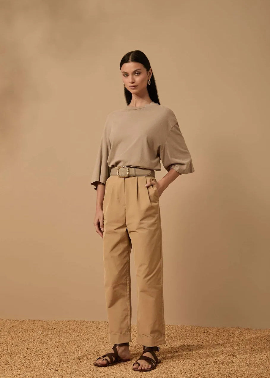 Woman wearing a beige outfit standing against a beige background