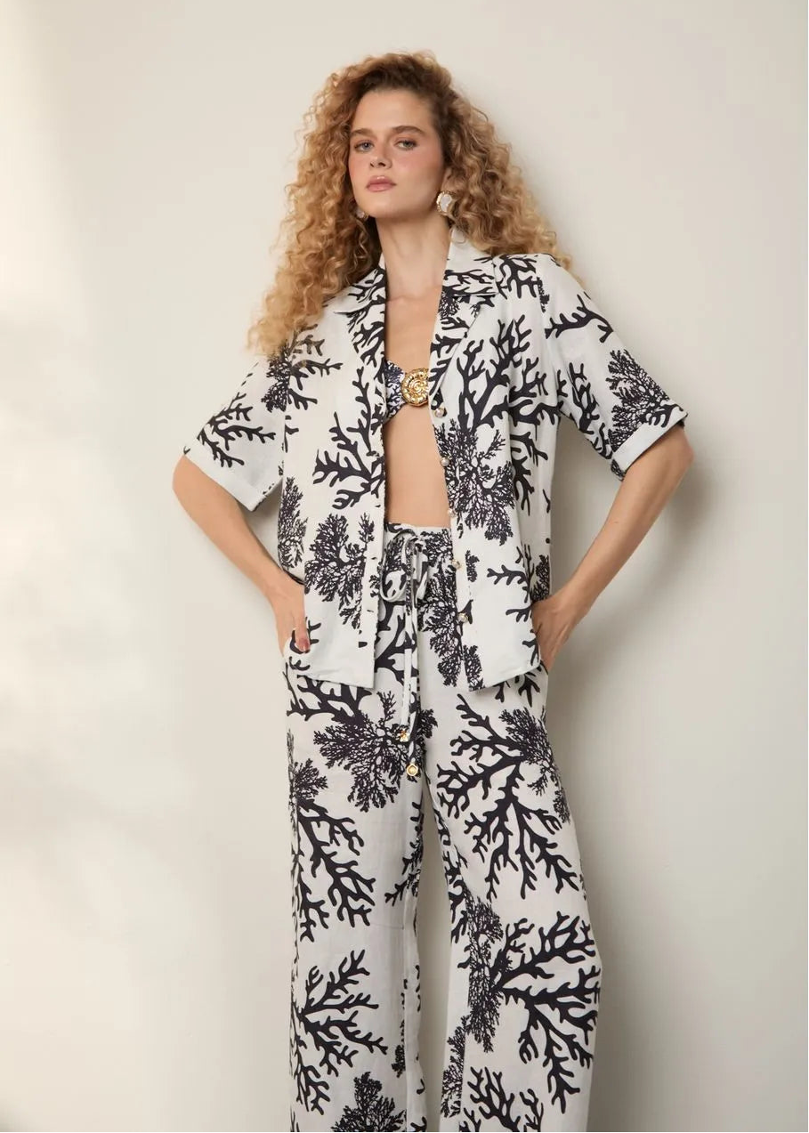 Woman wearing a black and white floral outfit against a plain background