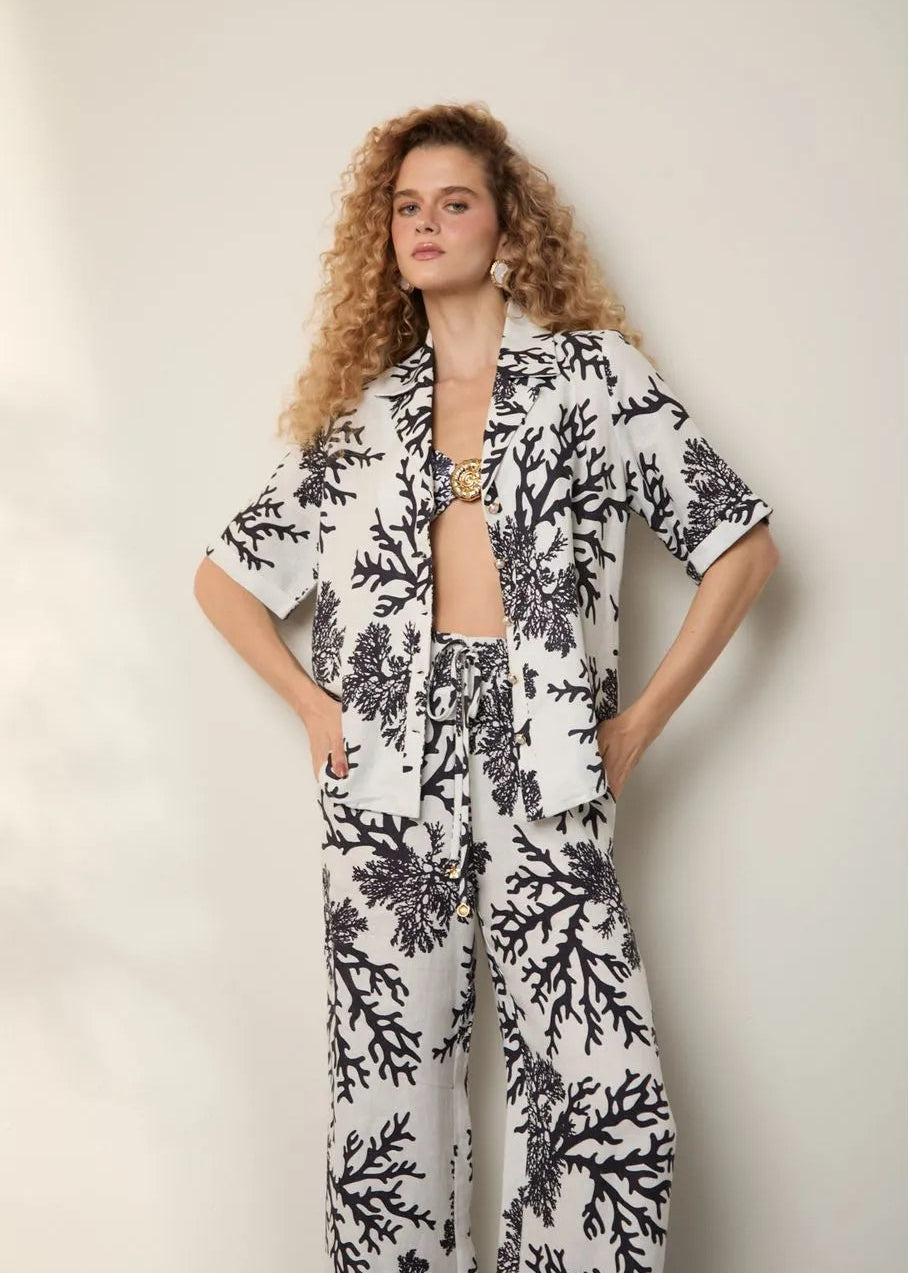 Woman wearing a black and white floral outfit against a plain background