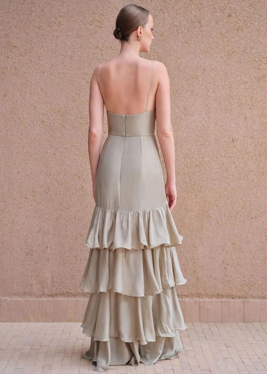 Woman wearing a strapless, tiered dress against a beige wall.