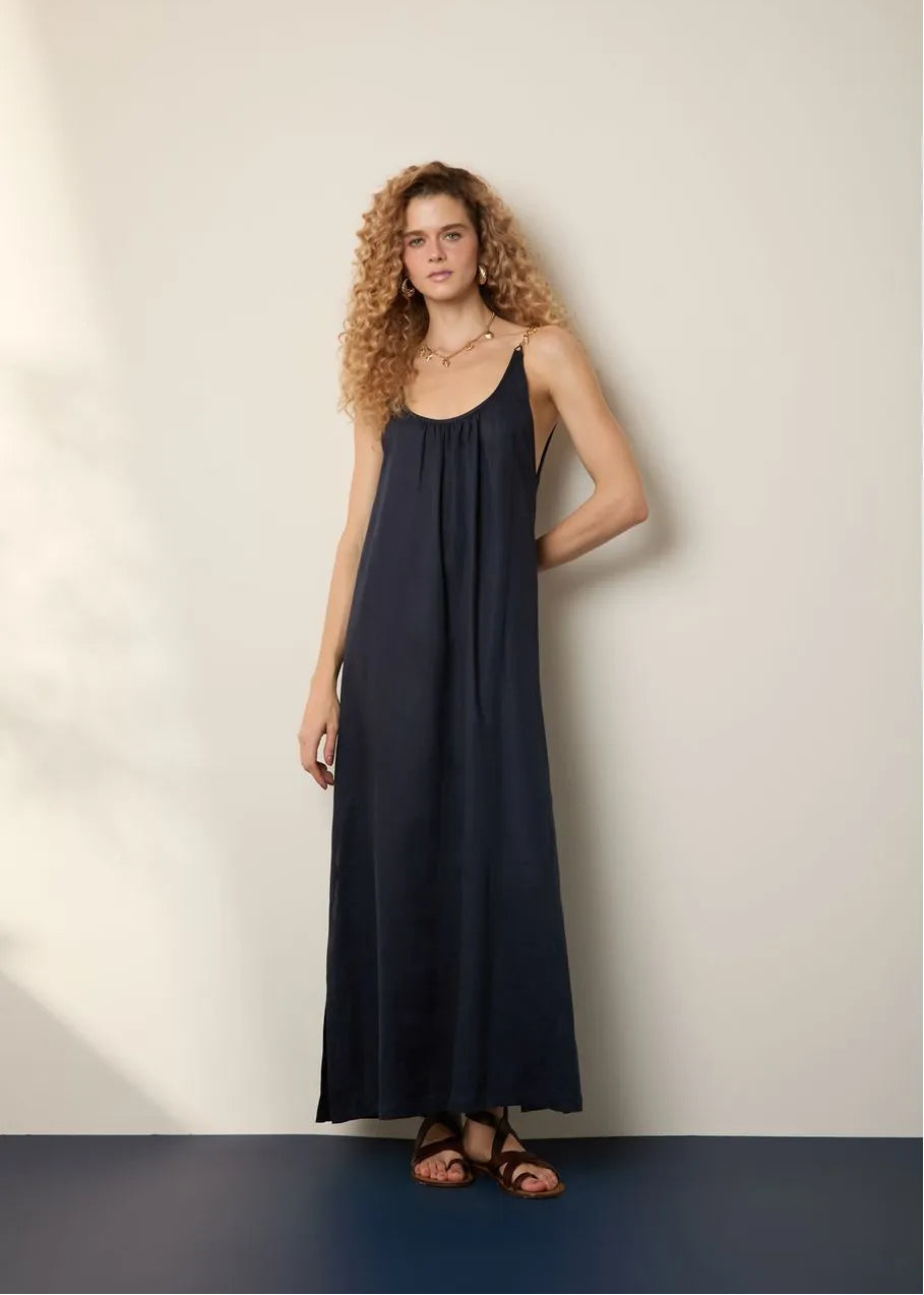 Woman wearing a long navy dress against a plain background