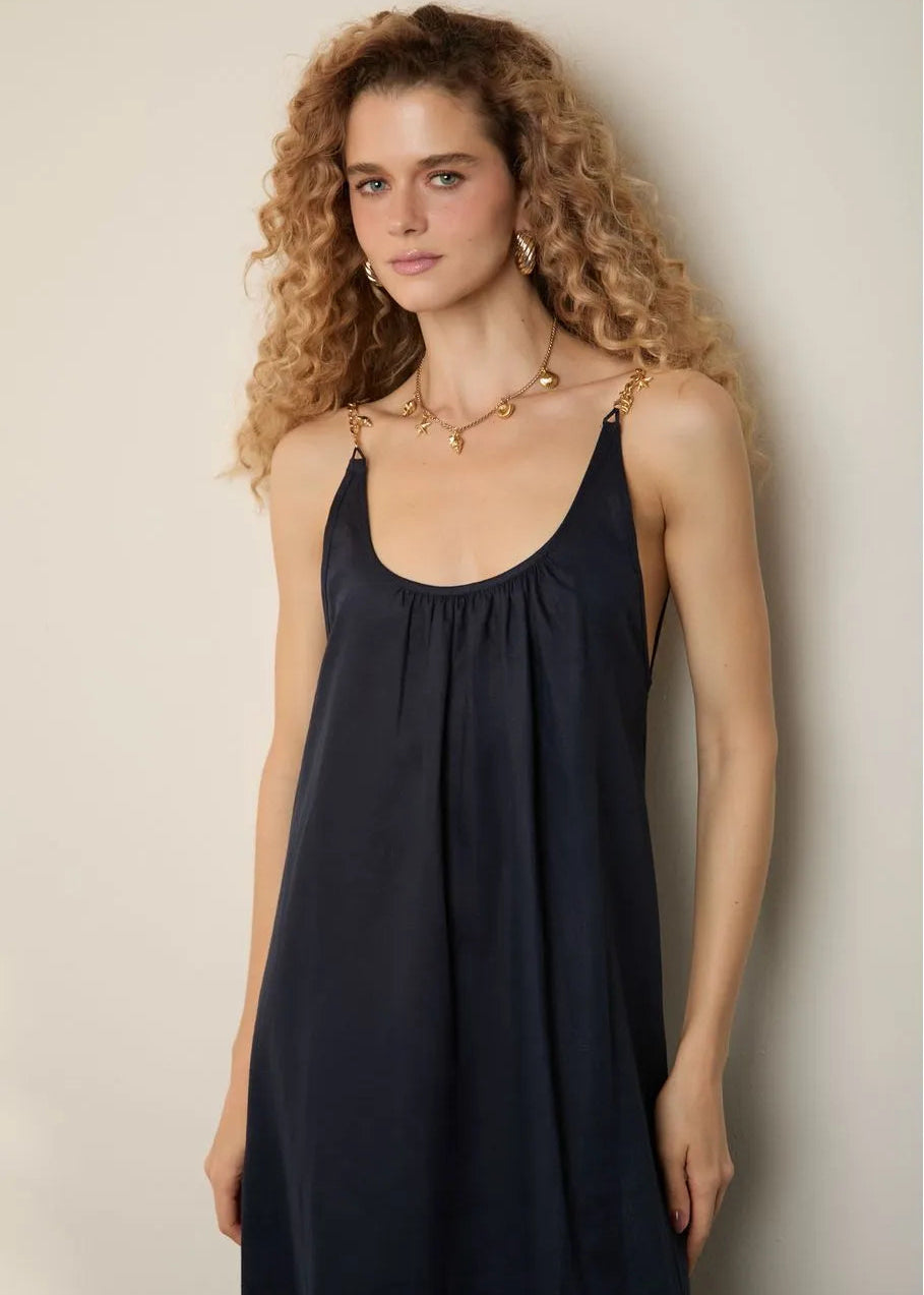 Woman wearing a black sleeveless dress against a beige background