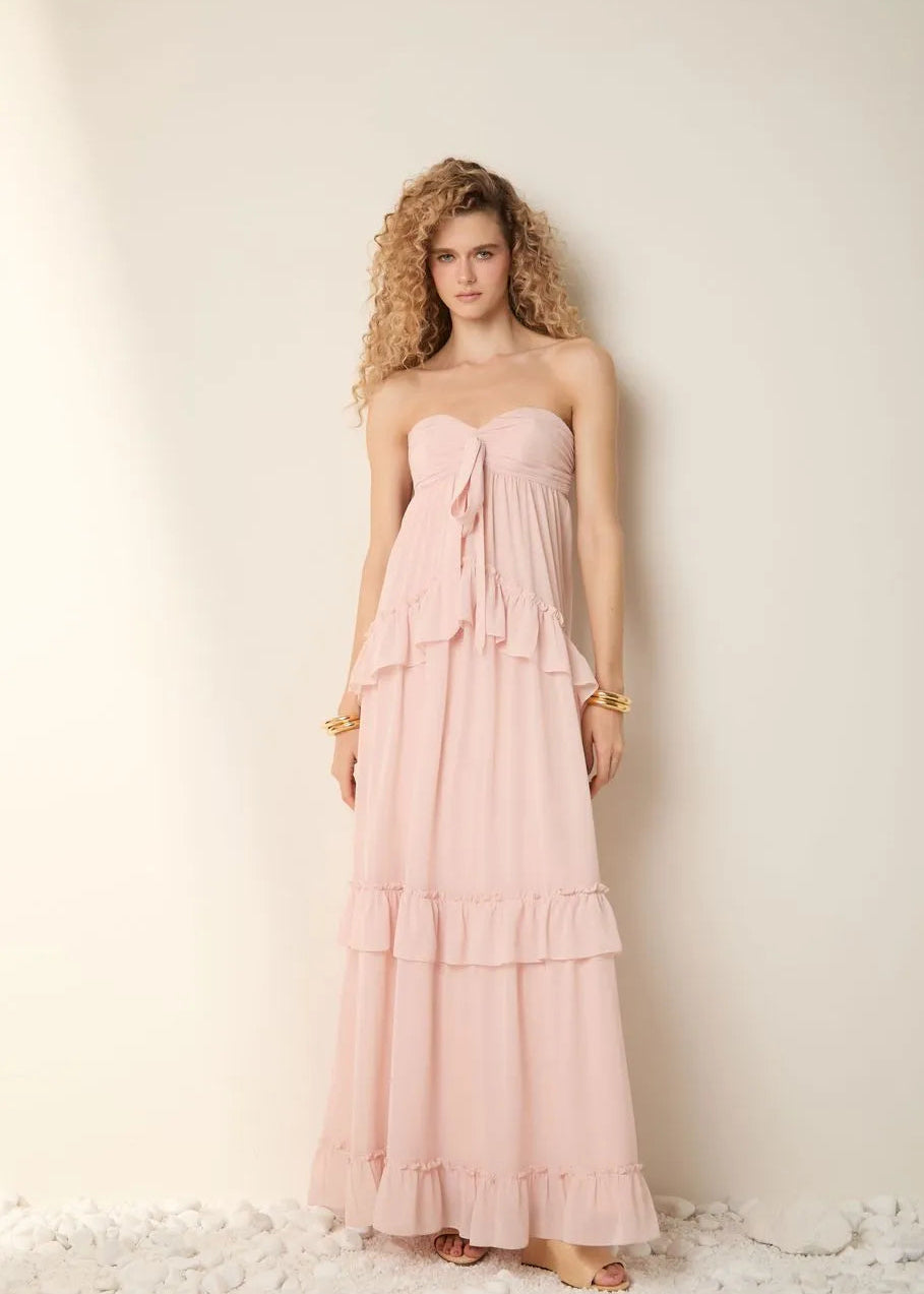 Woman wearing a pink strapless gown with ruffled layers against a plain background