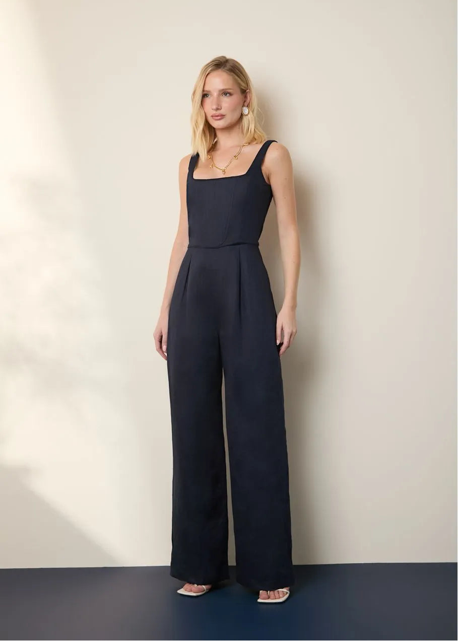 Woman wearing a navy blue jumpsuit against a plain background
