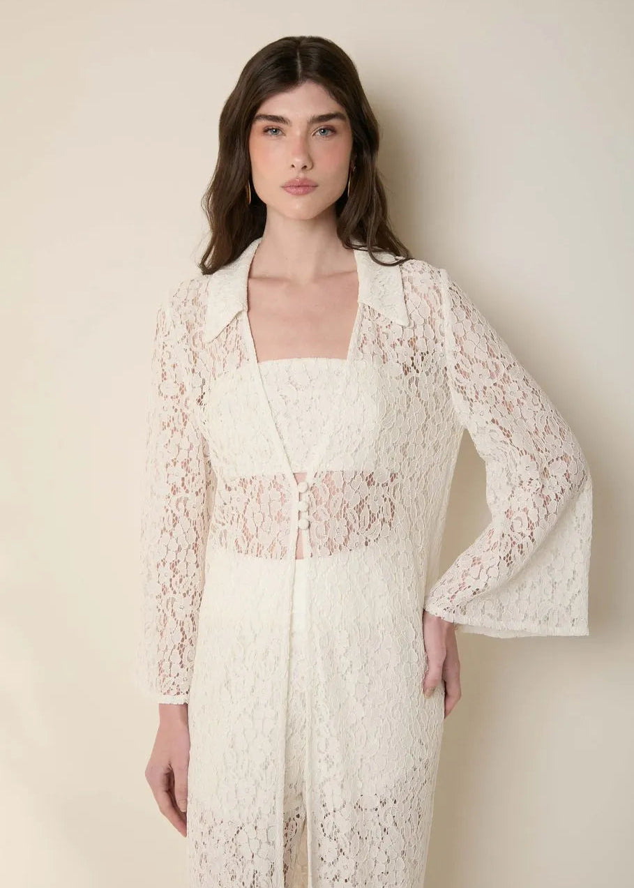 Woman wearing a white lace dress against a plain background