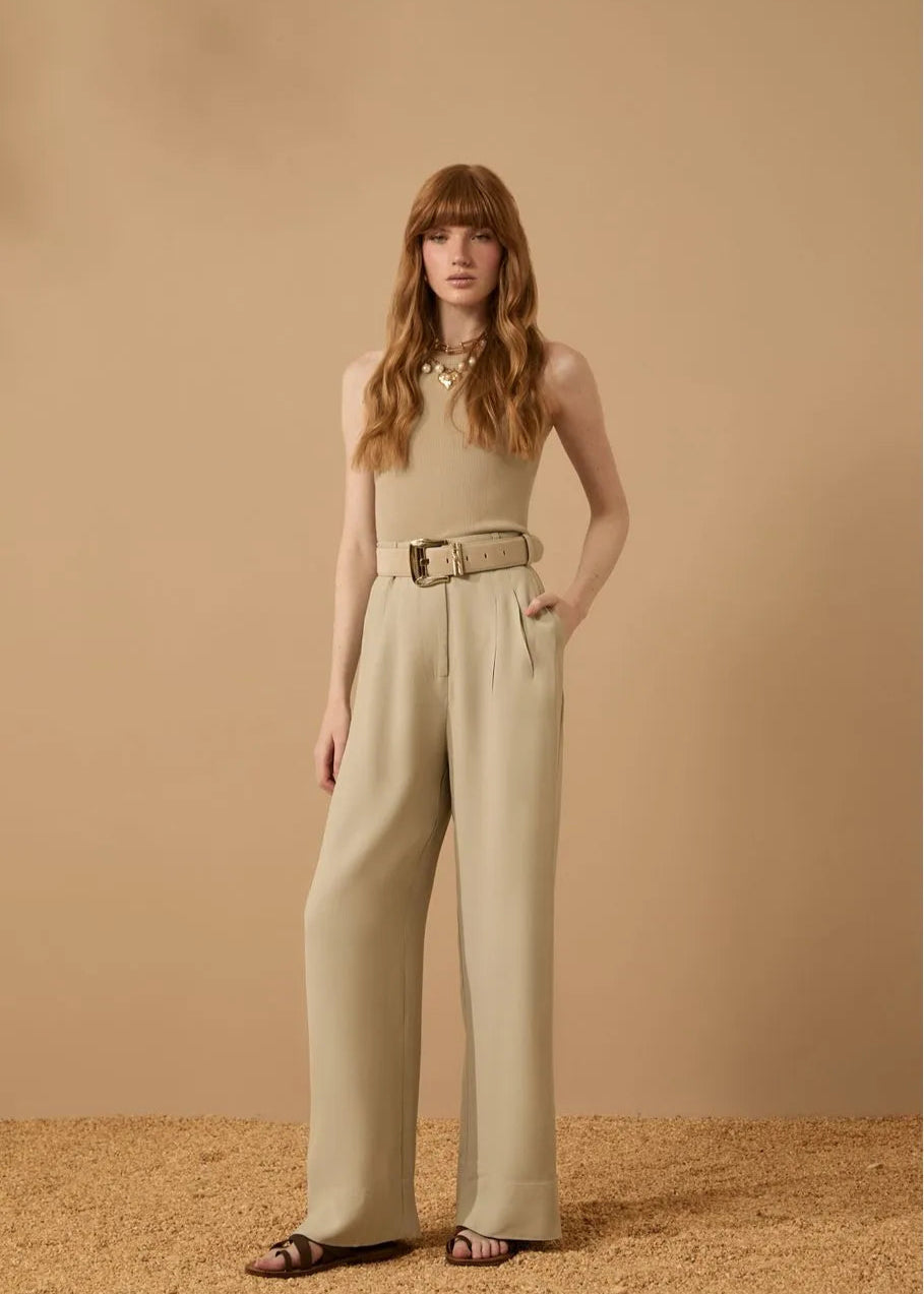 Woman wearing a beige sleeveless top and wide-leg pants against a beige background