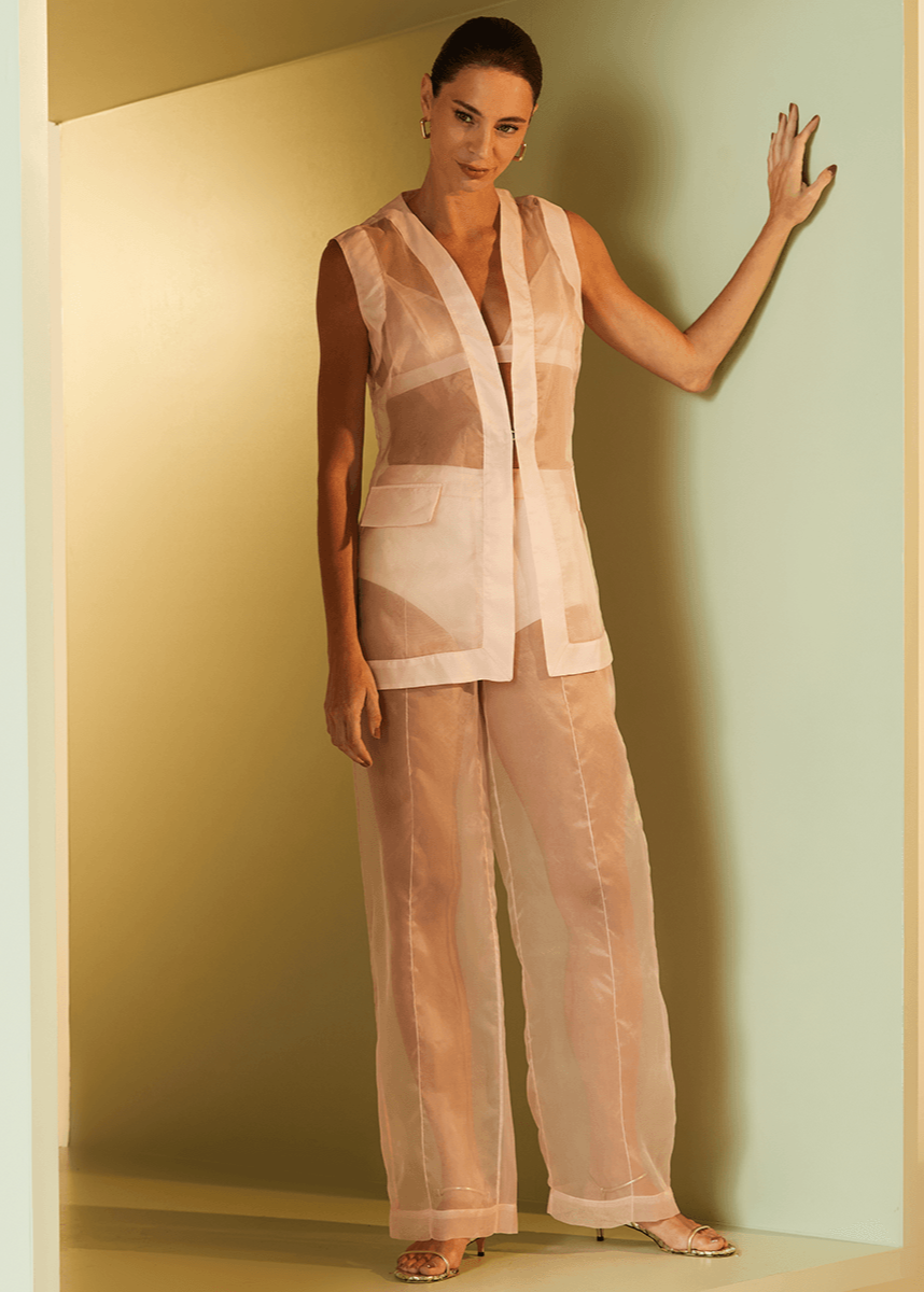 Woman wearing a sheer beige outfit against a neutral background