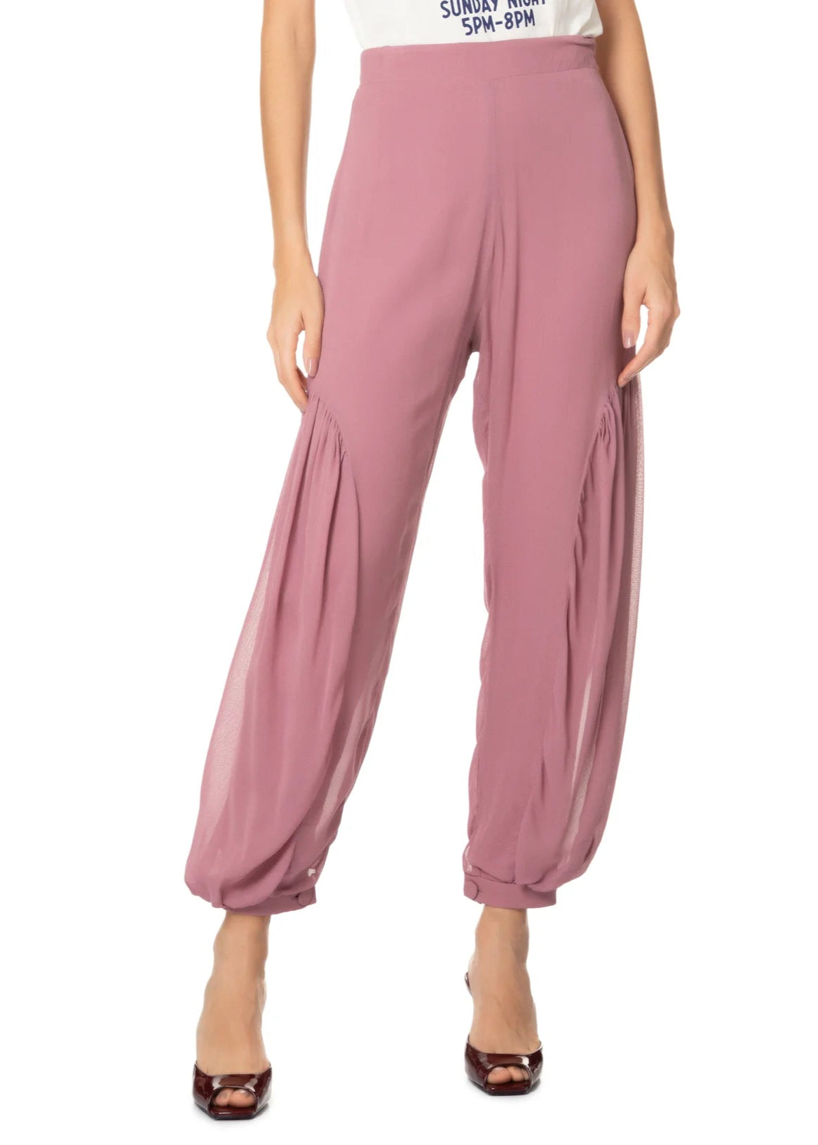 Pink harem pants worn by a person on a white background