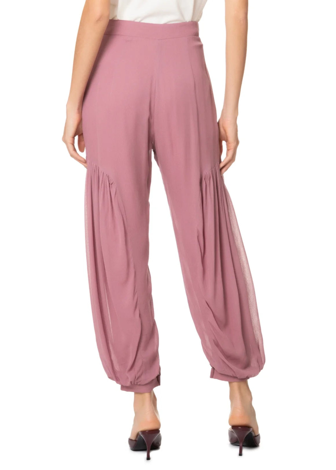 Pink harem pants worn by a person on a white background