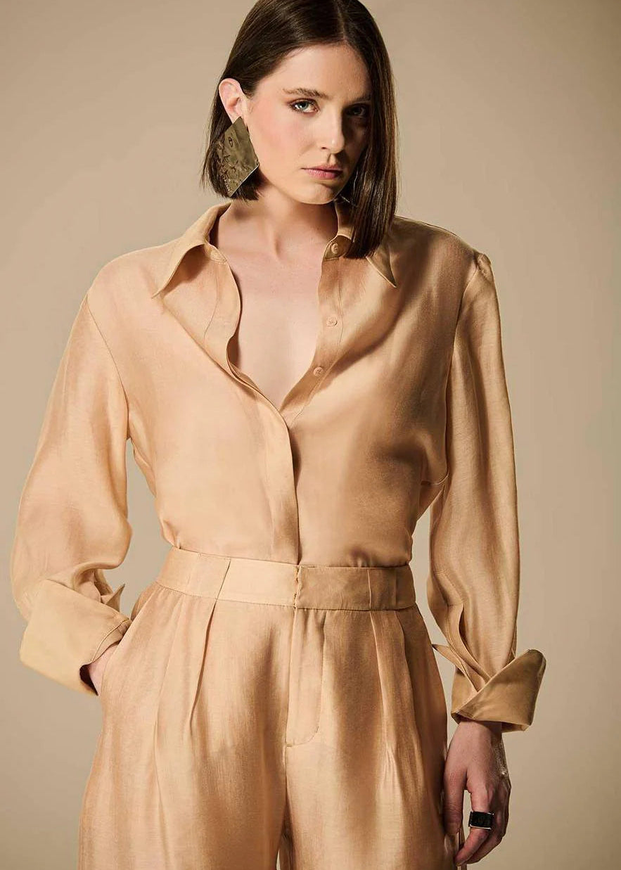 Woman wearing a beige satin jumpsuit against a beige background