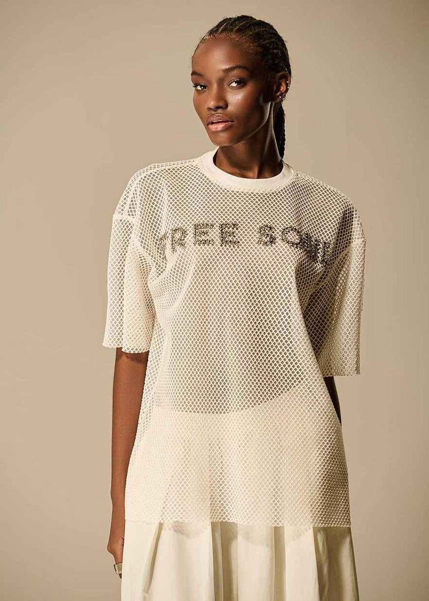 Woman wearing a mesh dress with 'FREE SOUL' text on a beige background