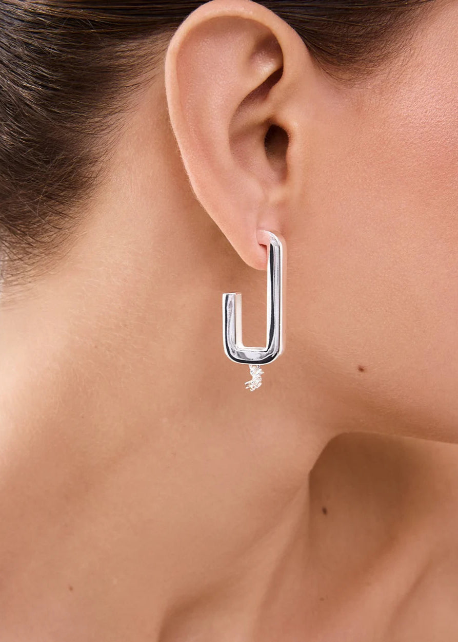 Silver hoop earring worn by a person with a neutral background
