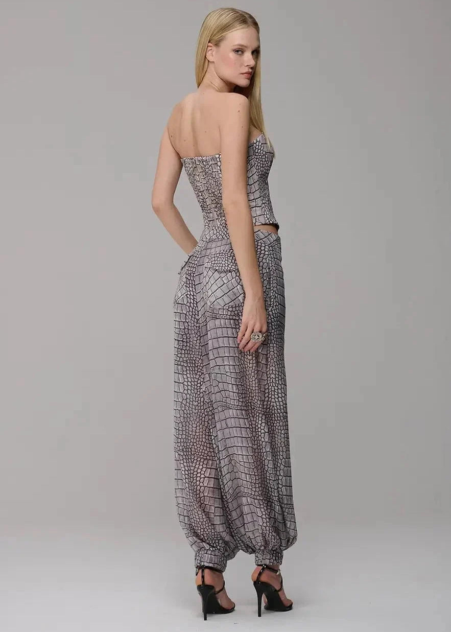 Woman wearing a strapless patterned jumpsuit on a plain background