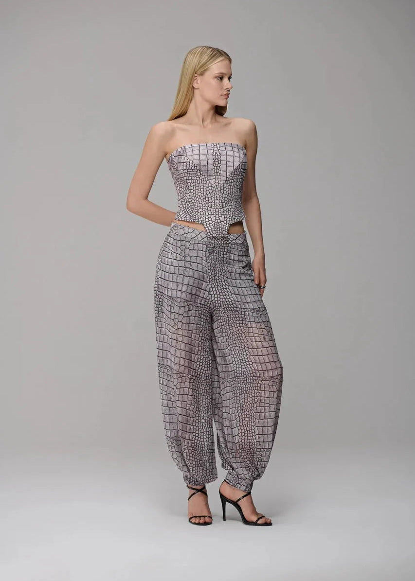 Woman wearing a strapless top and wide-leg pants with a grid pattern on a gray background