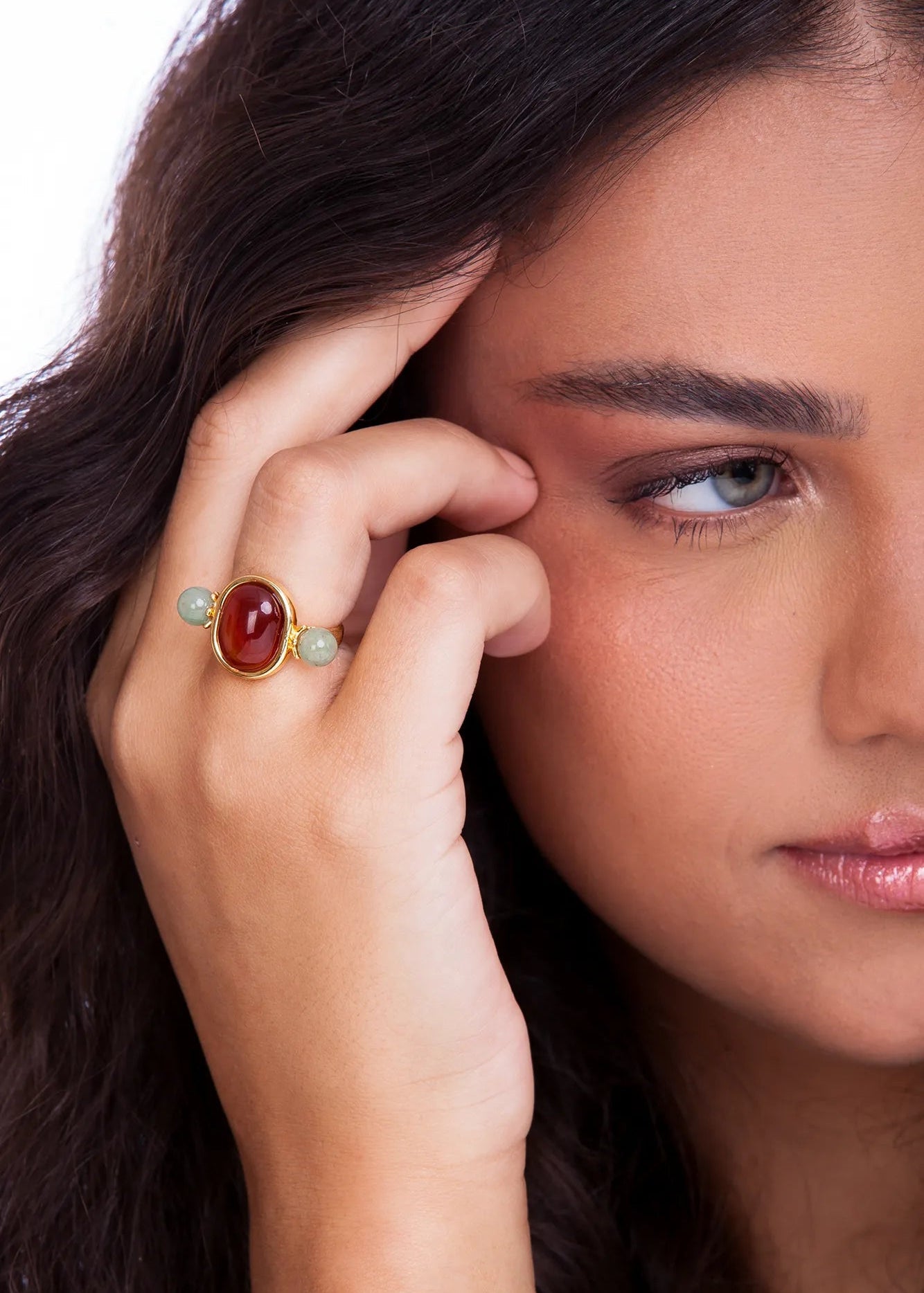 Woman wearing a ring with a red gemstone on a white background