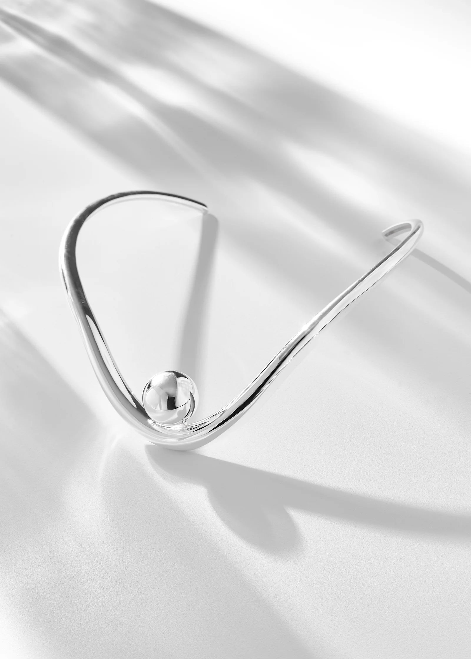 Silver bracelet on a reflective white surface
