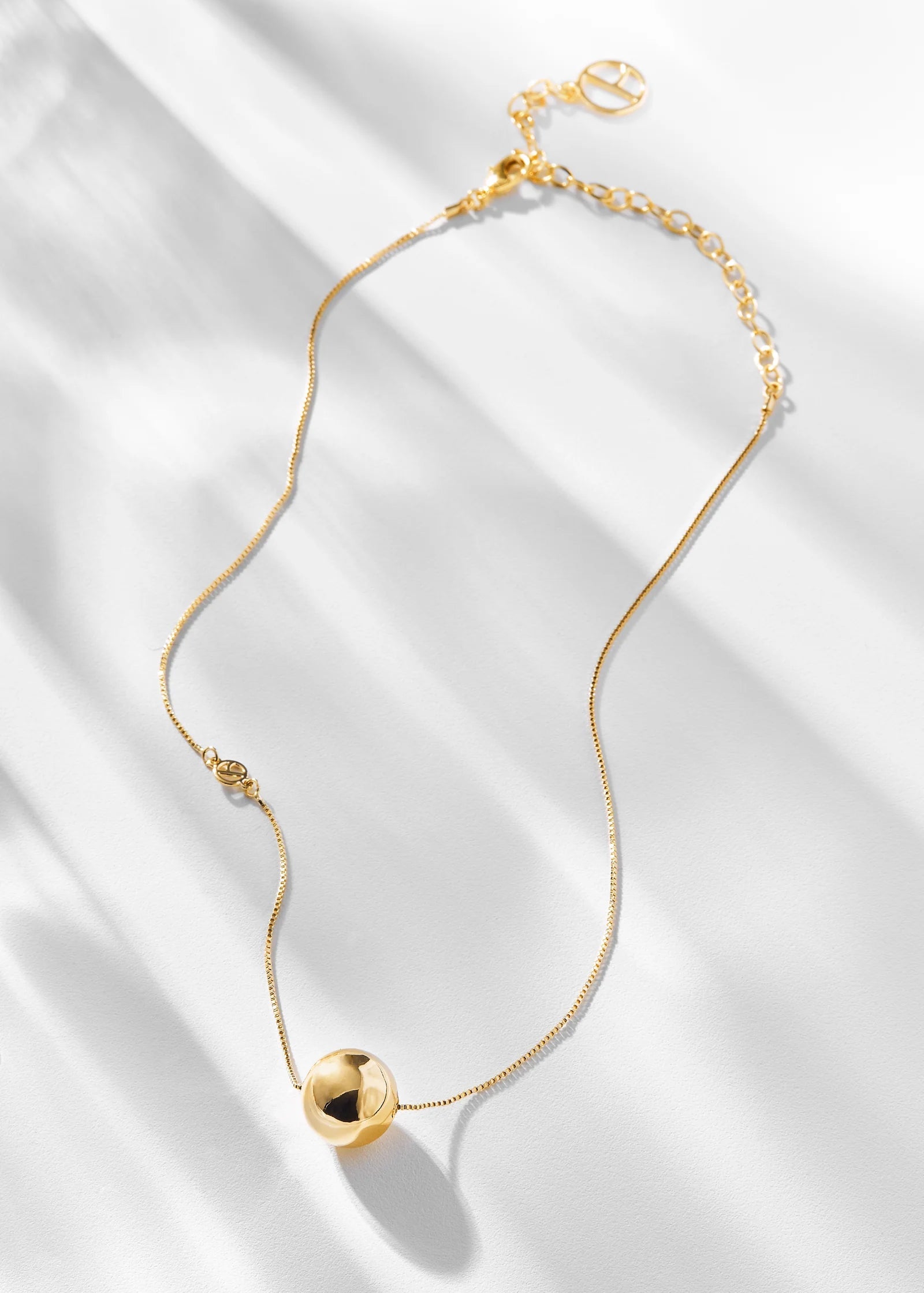 Gold necklace with a heart-shaped pendant on a white fabric background