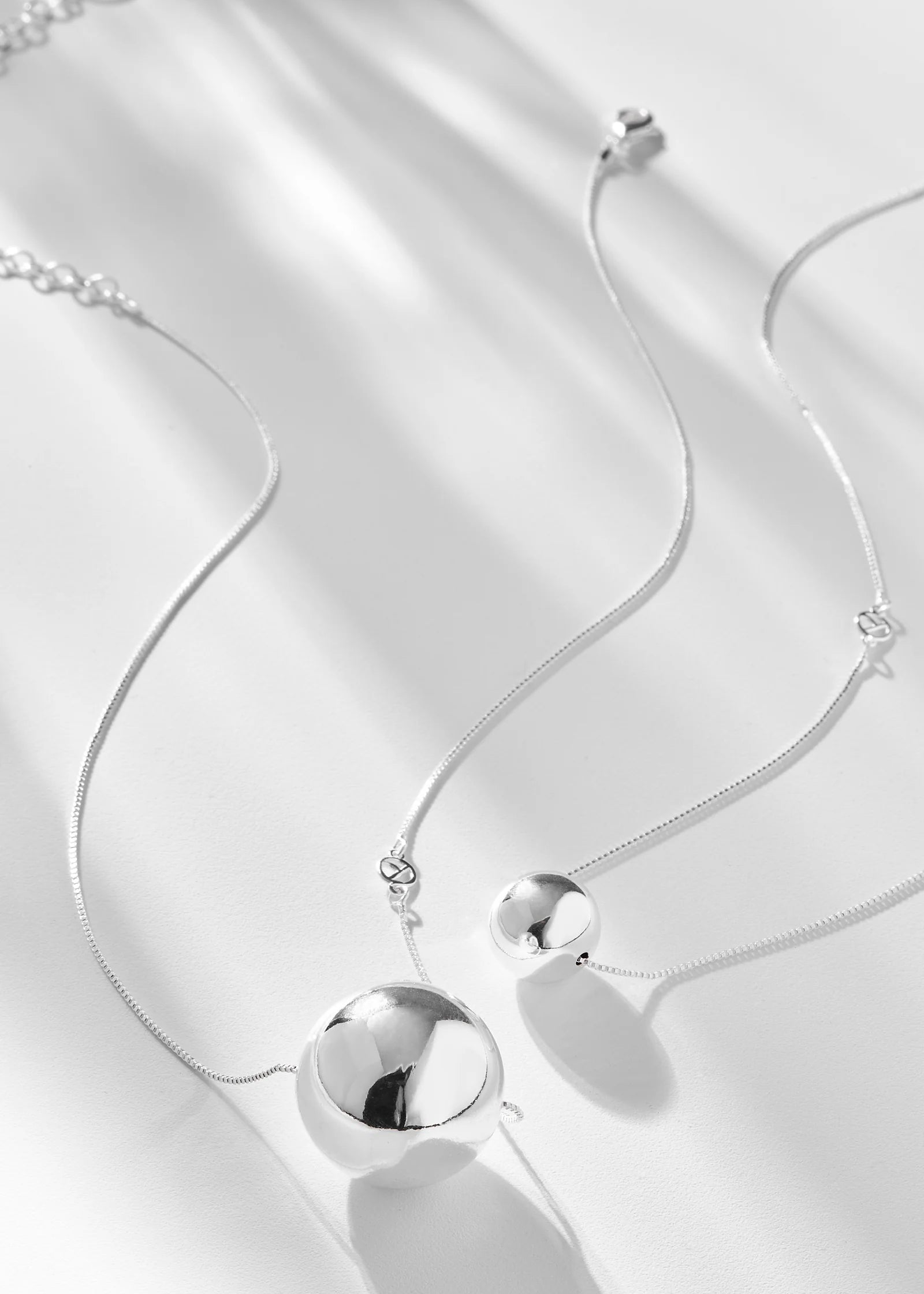 Silver necklace with spherical pendants on a white background