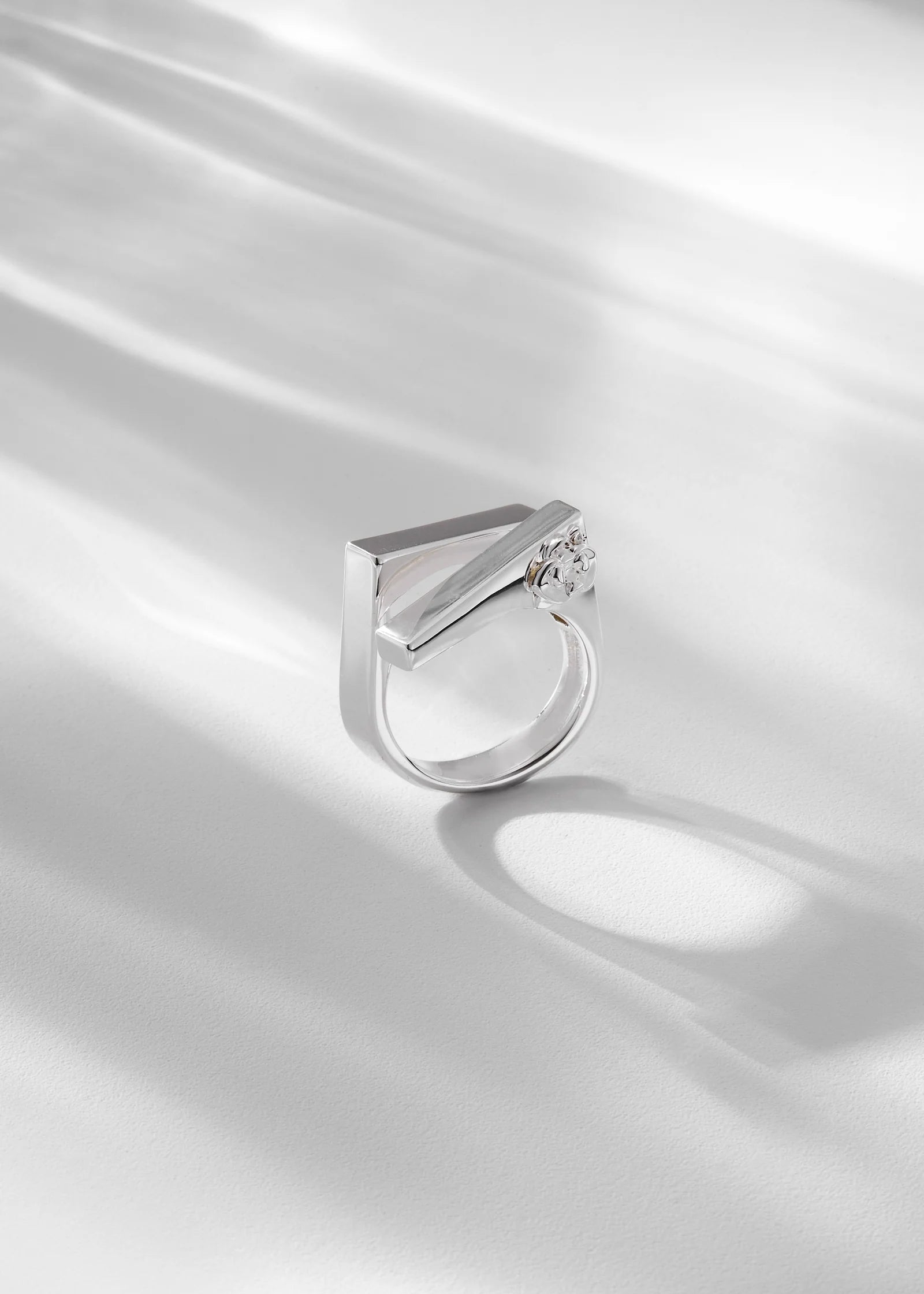 Silver ring with a unique design on a white satin background