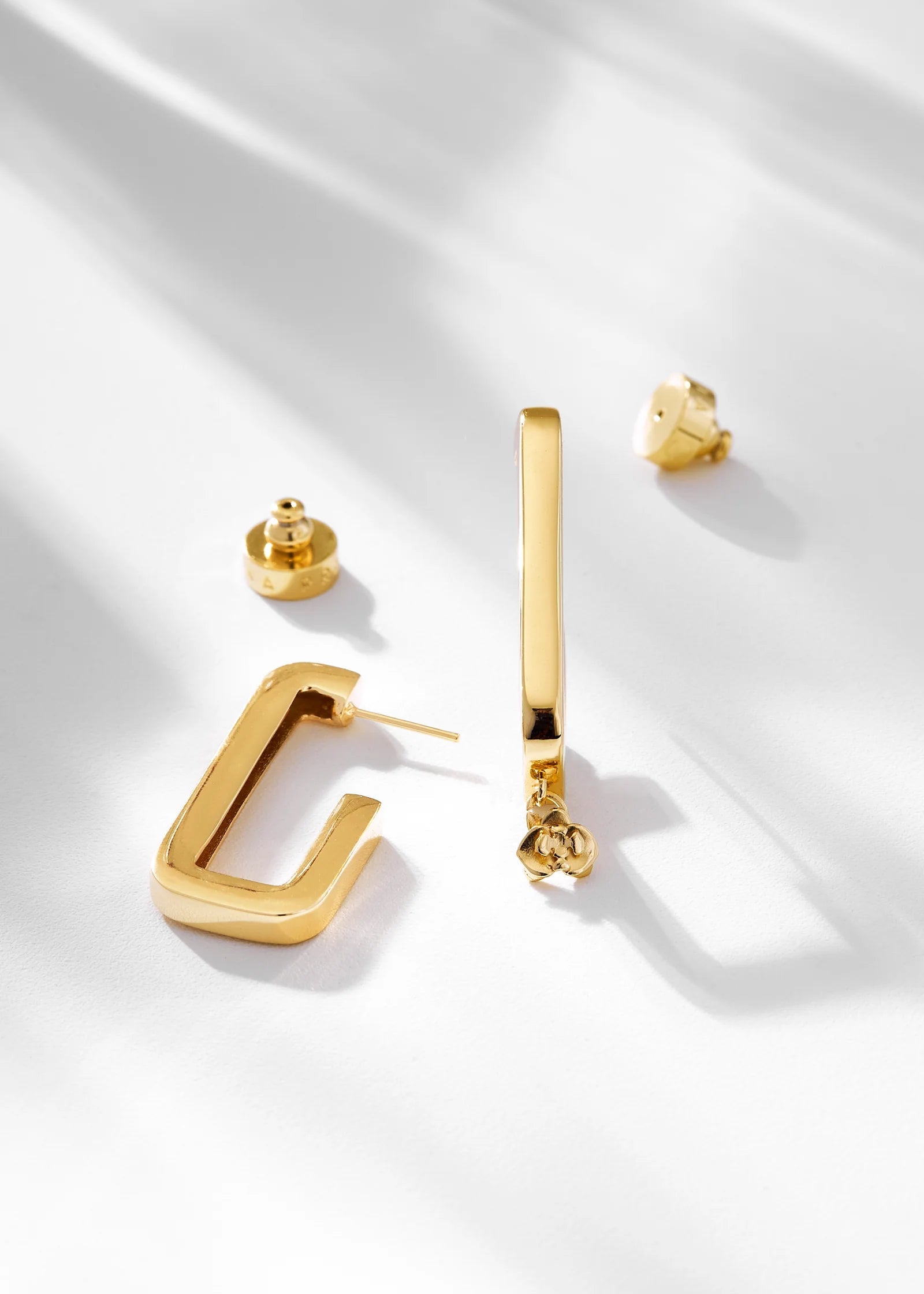 Gold earrings on a white fabric background