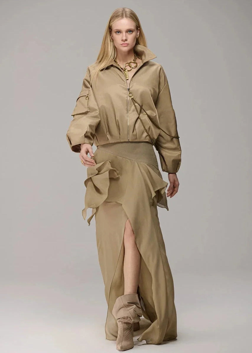 Woman wearing a beige outfit with a top and skirt on a gray background