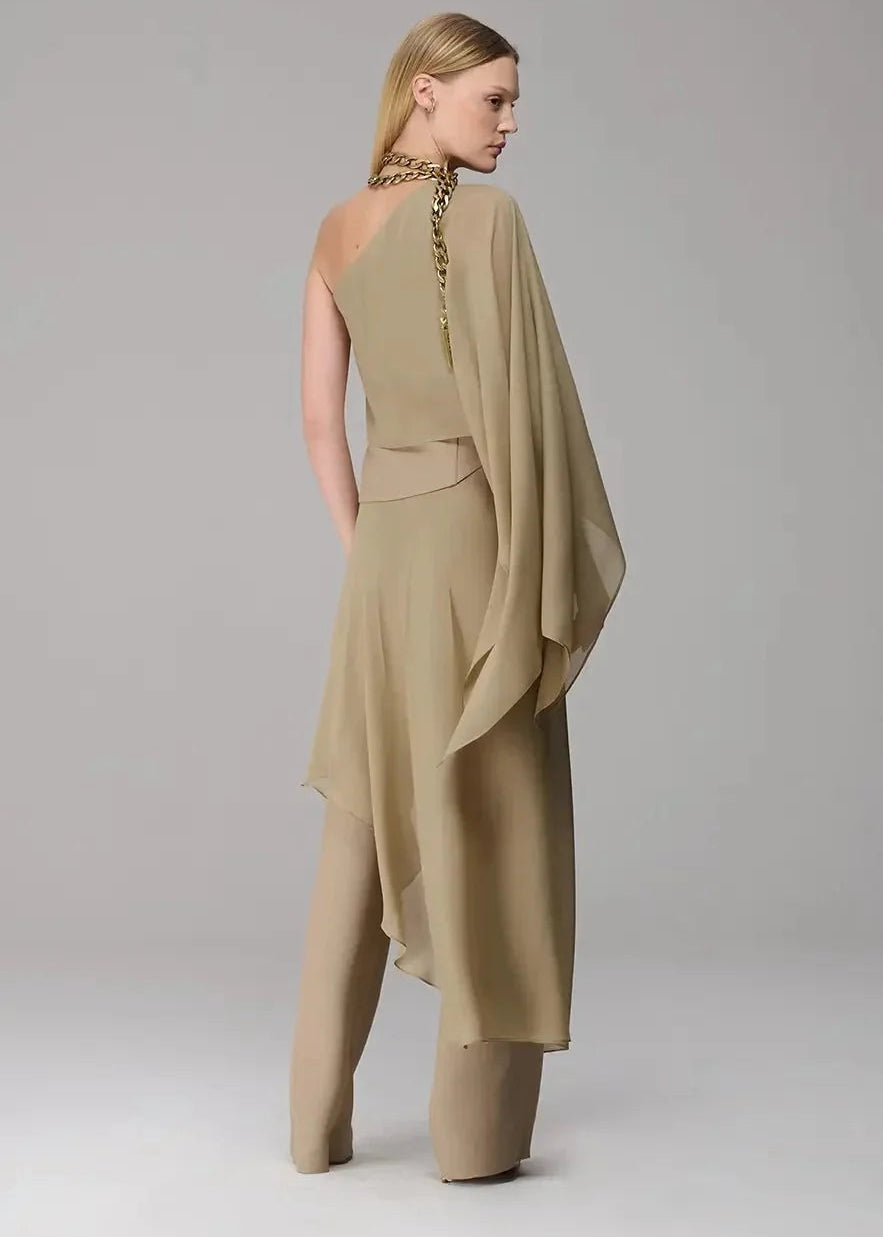 Woman wearing a beige one-shoulder dress with a draped effect on a plain background