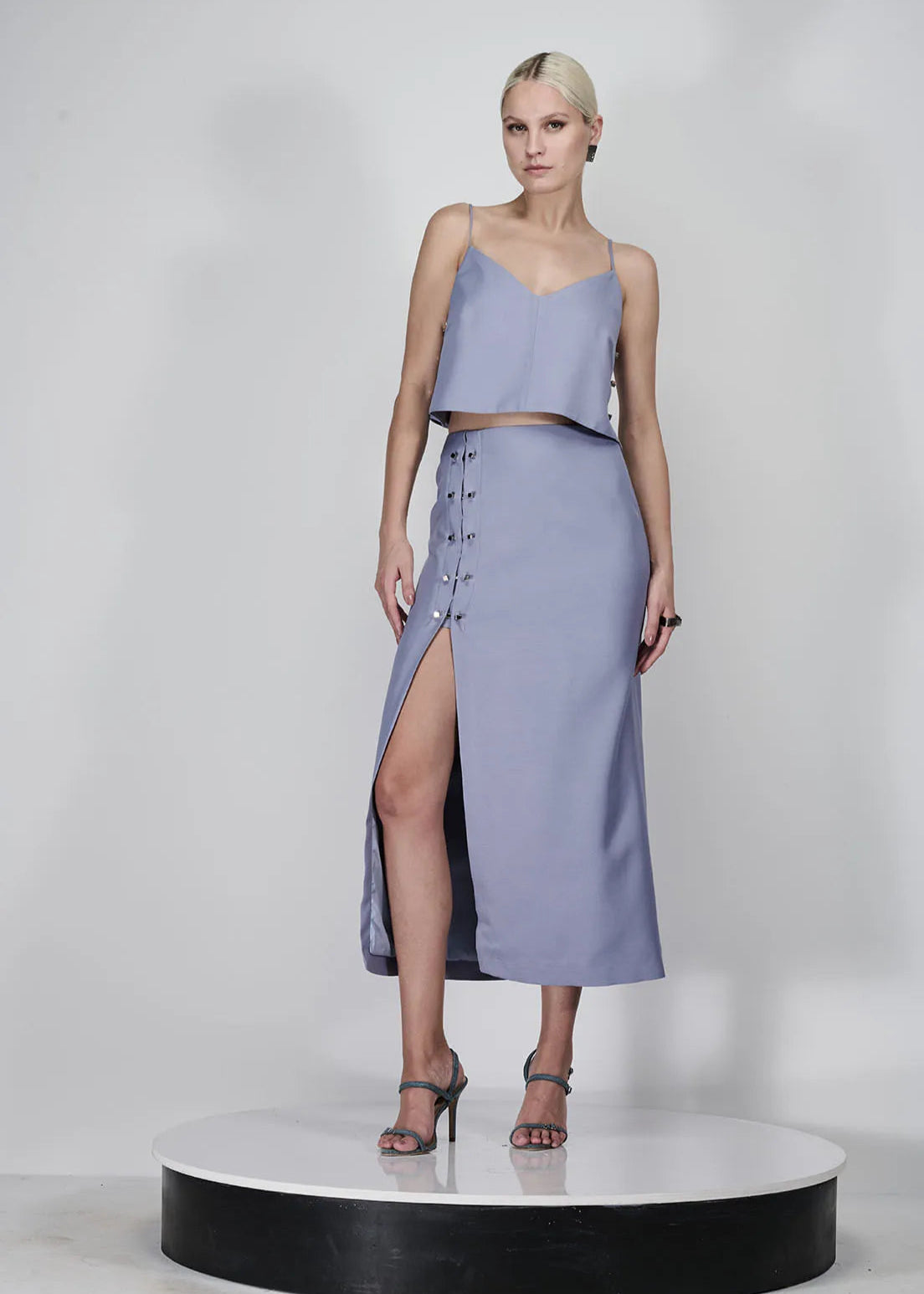Woman wearing a light purple two-piece outfit with a slit skirt on a white background
