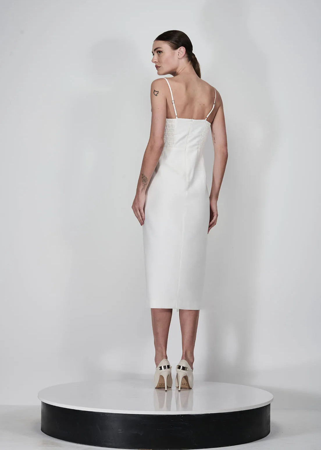 Woman wearing a white slip dress on a plain background