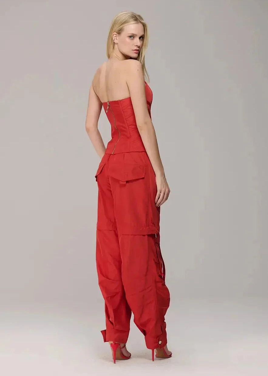 Woman wearing a red strapless jumpsuit on a plain background