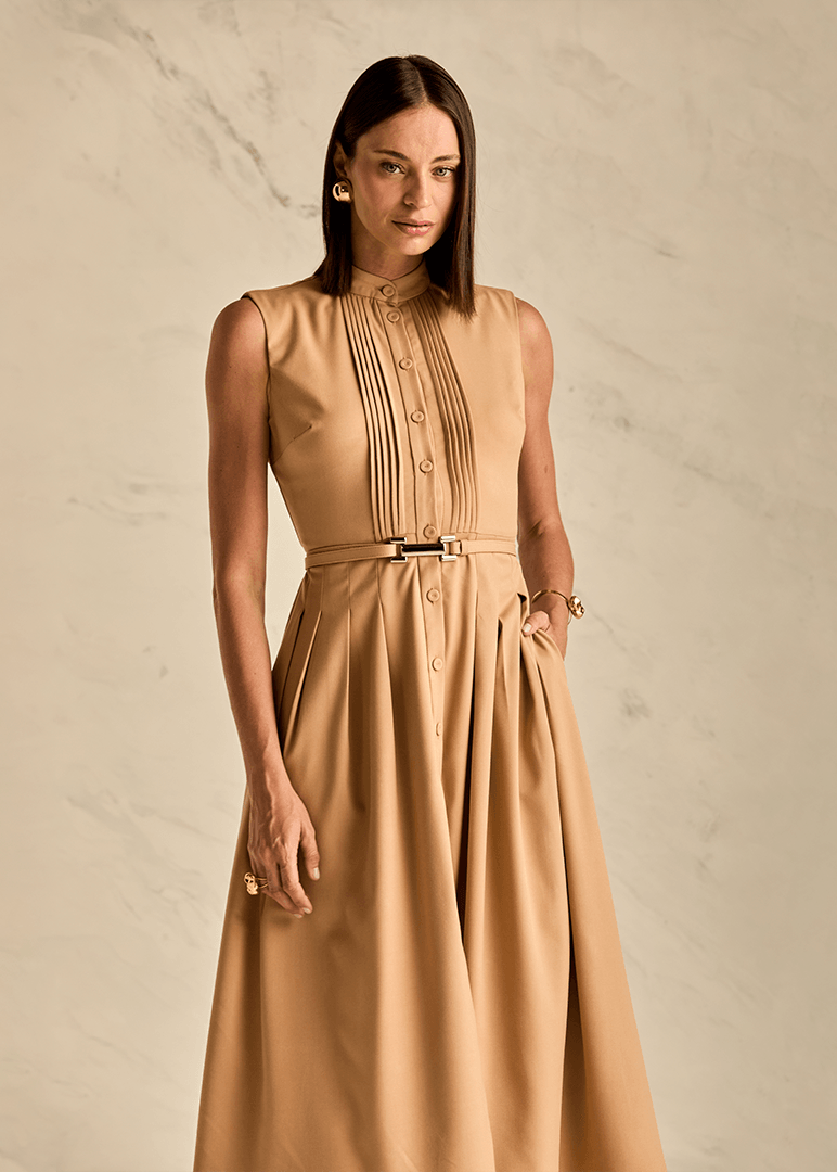 Woman wearing a beige sleeveless dress against a neutral background