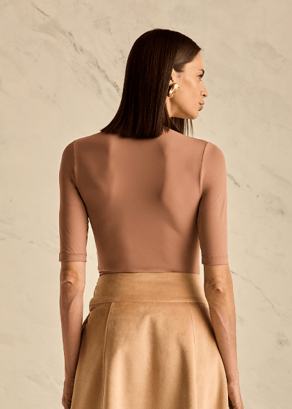 Woman wearing a beige top with a plain background