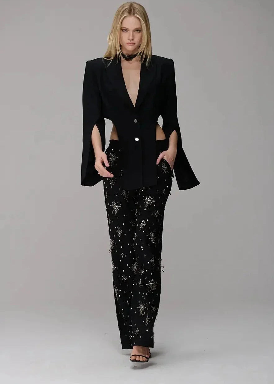 Woman wearing a black suit with star-patterned pants on a gray background