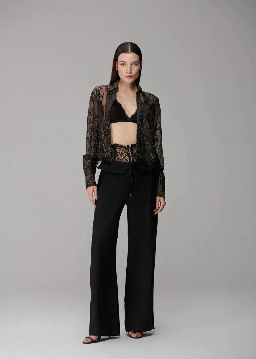 Woman wearing a patterned blouse and black pants on a gray background