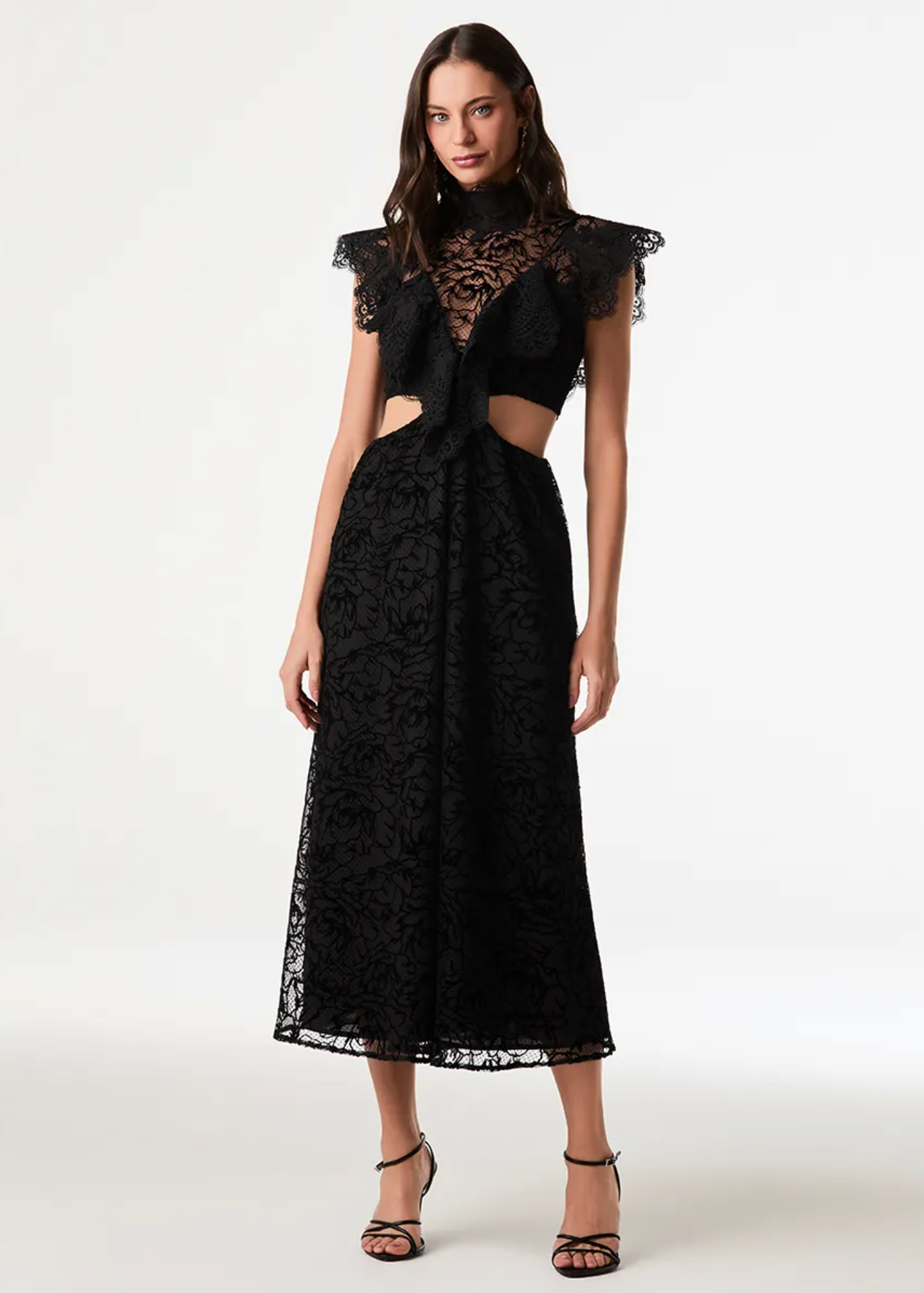 A model wearing a black lace midi dress with ruffled cap sleeves, a high-neck lace overlay, and side cutouts, paired with black strappy heels against a plain white studio background.