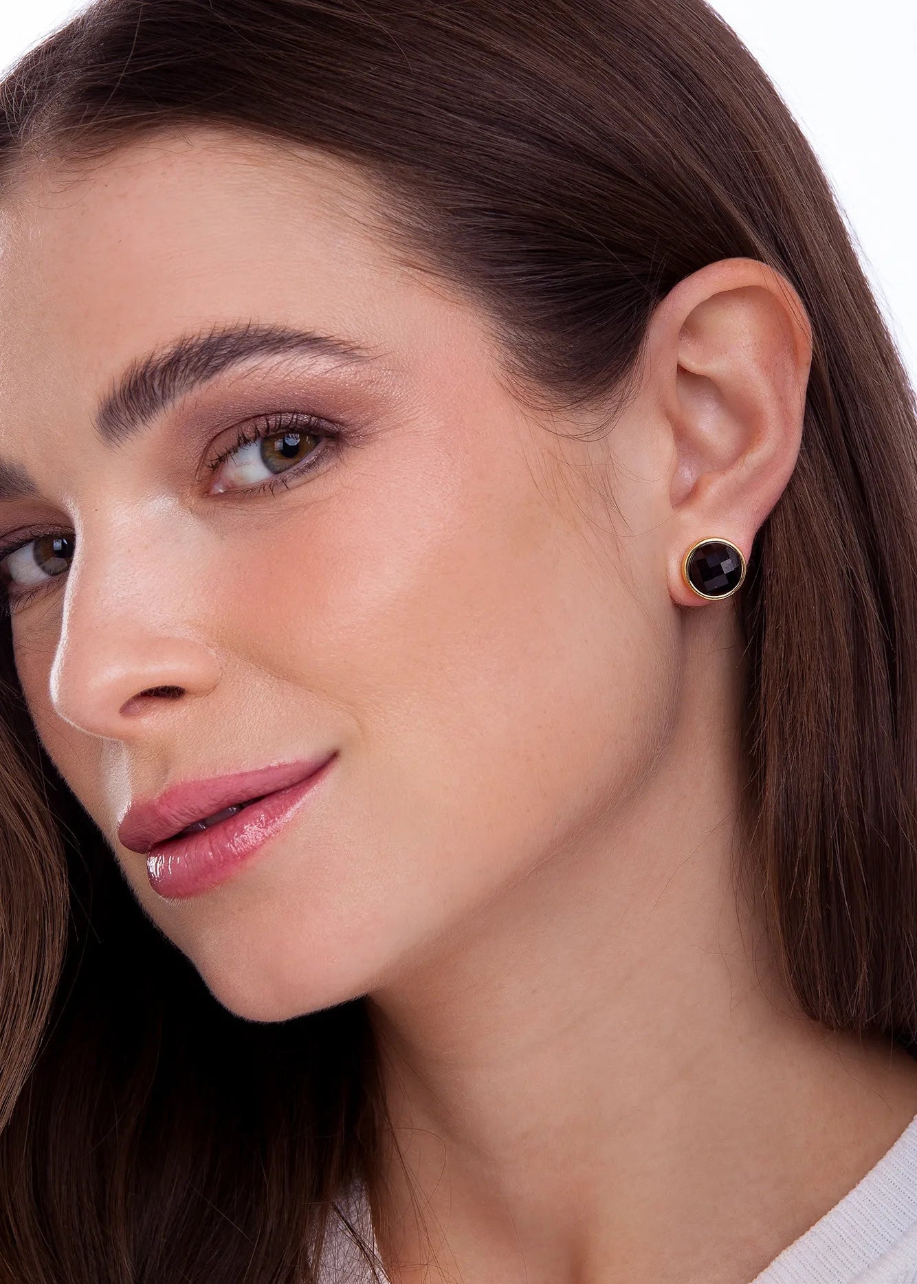 Close-up of a woman wearing a black earring on a white background