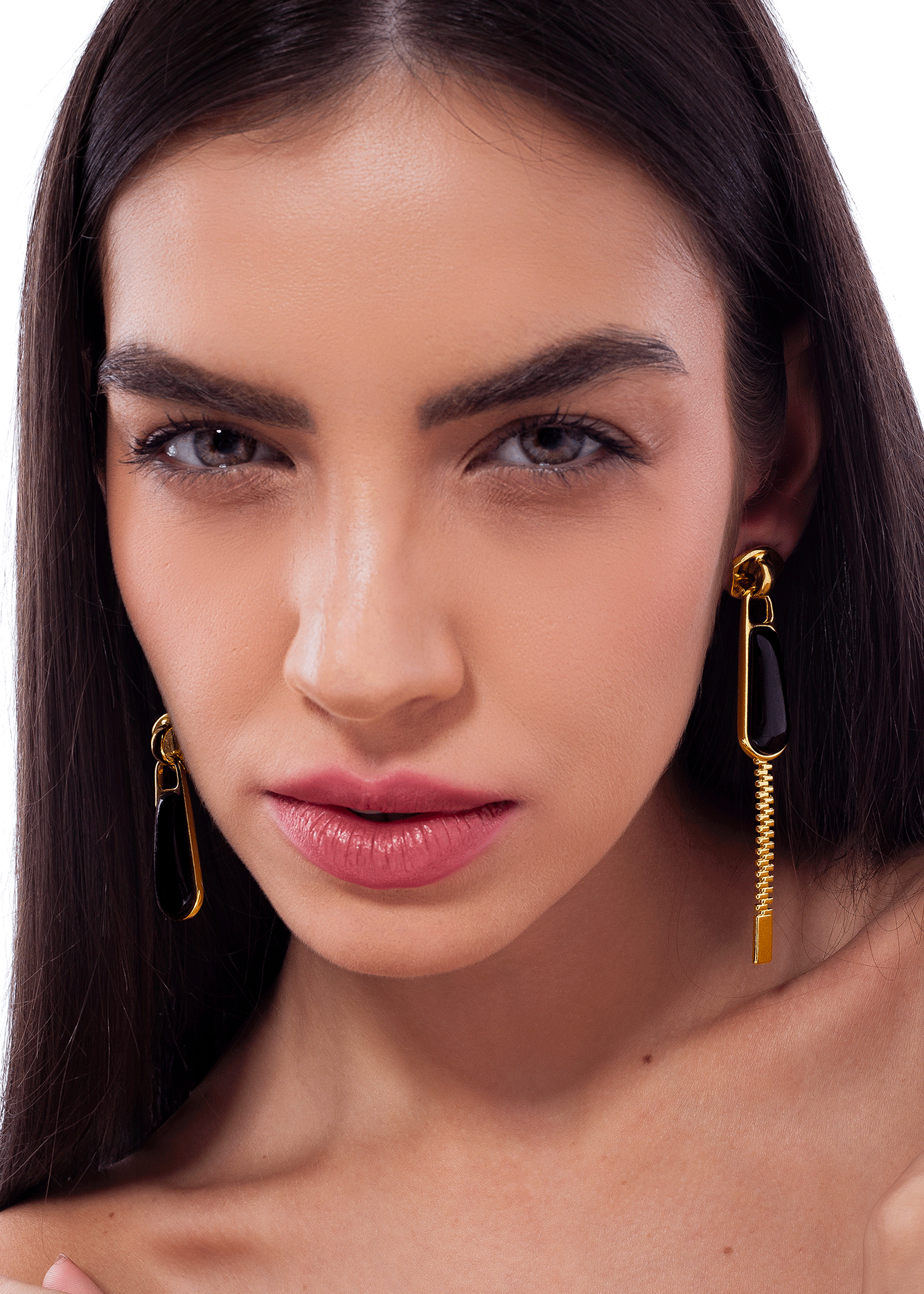 Close-up of a woman wearing gold earrings with a plain background