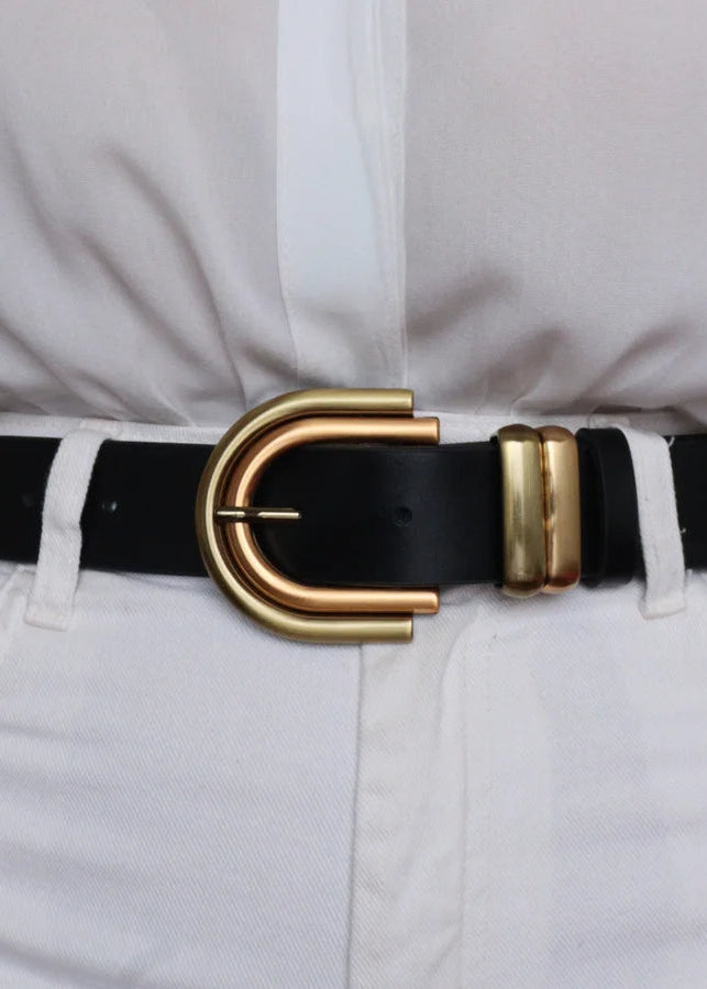 Black belt with a gold buckle worn by a person in a white shirt and light-colored pants.