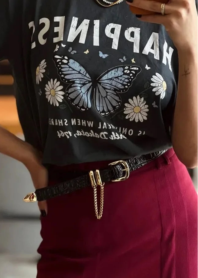 Person wearing a black t-shirt with a butterfly graphic and text, standing indoors.